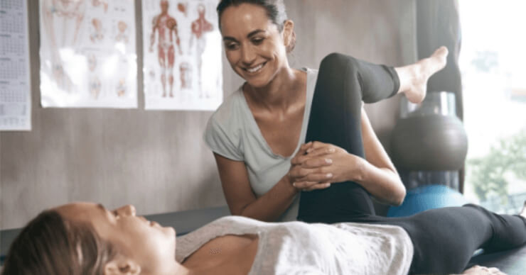 Physiotherapist helping patient with left leg stretch