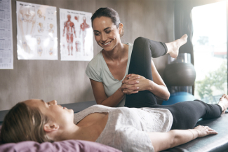 Physiotherapist helping patient with left leg stretch 